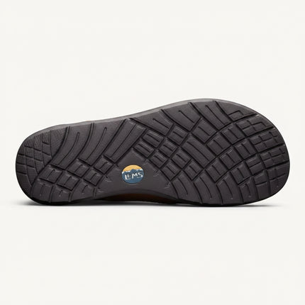 Underside of a dark brown shoe with a textured sole and a small circular Lems logo