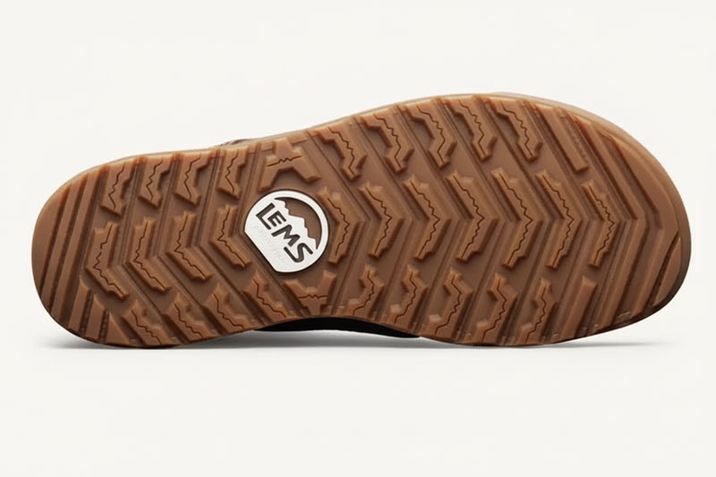 Brown rubber sole of a shoe with a textured tread pattern and a white Lems logo