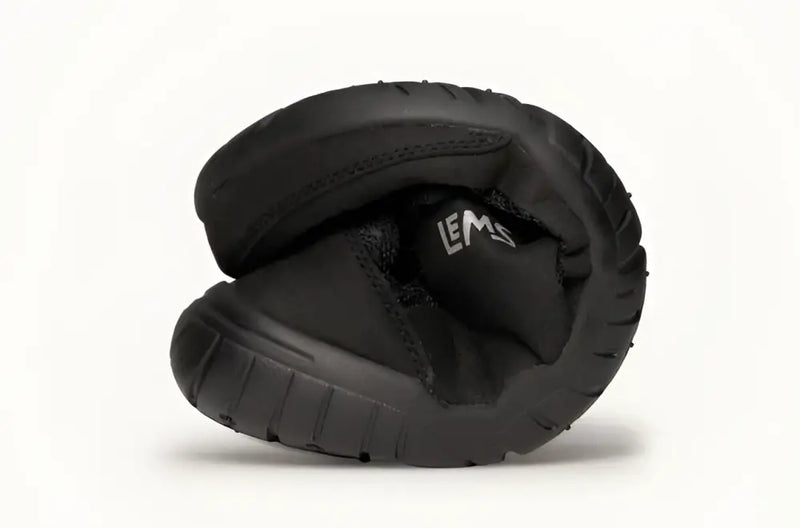 Black Lems shoe folded in half to show flexibility