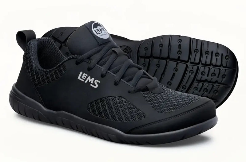 Pair of black Lems Primal Pursuit shoes with textured mesh and solid black accents