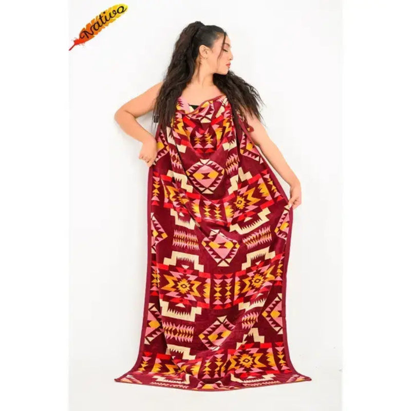 Woman wrapped in a burgundy blanket with a geometric pattern in yellow, pink, and orange