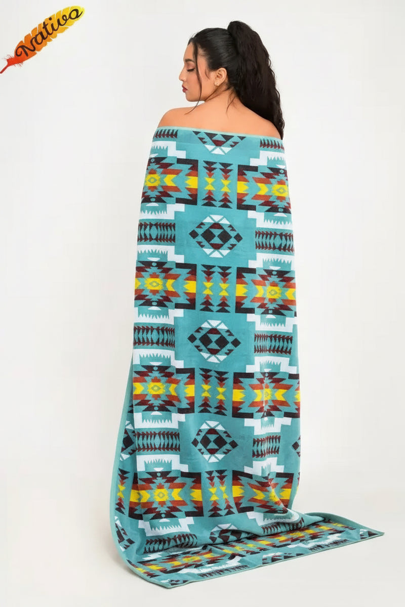 Woman wrapped in a turquoise blanket with geometric patterns in yellow, red, black, and white