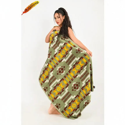 Woman kneeling, draped in a green, yellow, and brown patterned blanket
