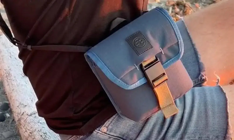 Person wearing a grey hip bag with a gold buckle and strap