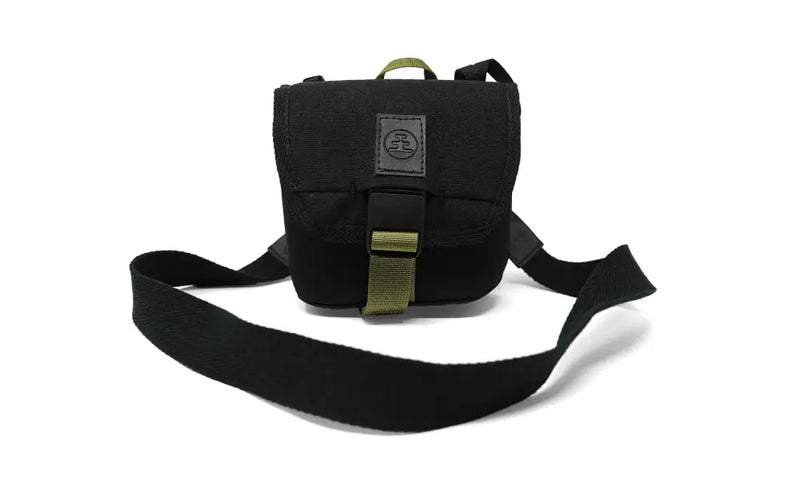 Black camera bag with a green strap and buckle, on a white background