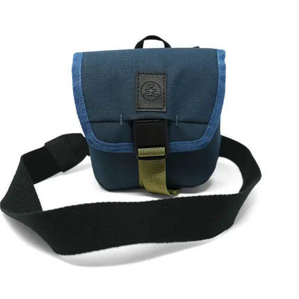 Blue camera bag with a black strap and olive green buckle on a white background