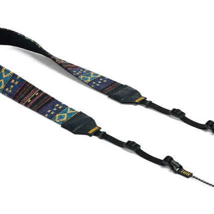 Blue and yellow patterned camera strap with black leather accents and adjustable buckles