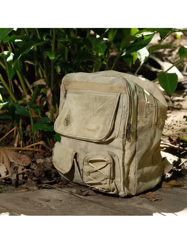 Light brown canvas backpack with multiple pockets and zippers, resting on a wooden surface with green foliage