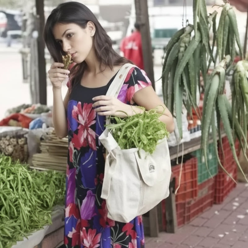 Woman in a floral dress holding a bag of green vegetables at a market stall