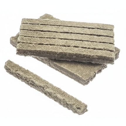 Several rectangular pieces of light brown, fibrous material with horizontal grooves, on a white background
