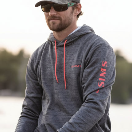Man wearing a grey hoodie, sunglasses, and a cap, holding fishing gear