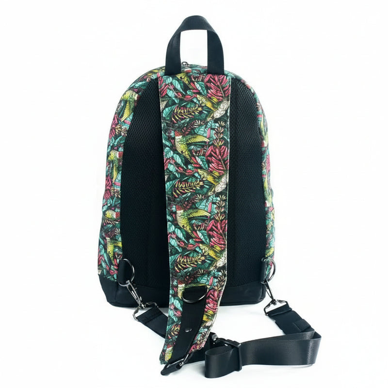 Back of a backpack with a colorful tropical bird and leaf pattern, black mesh back panel, and black strap