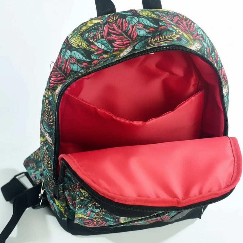 Open backpack with a red interior lining and a tropical leaf pattern on the exterior