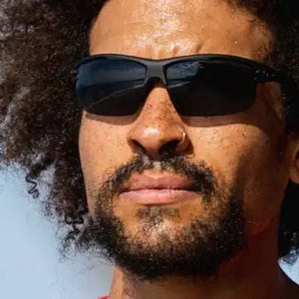 Man with curly hair and beard wearing black sunglasses