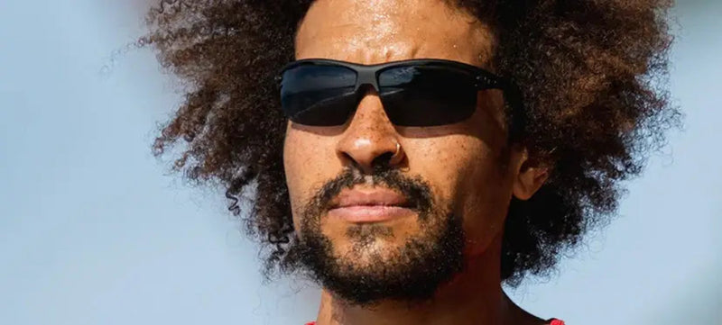 Man with curly hair and beard wearing black sunglasses