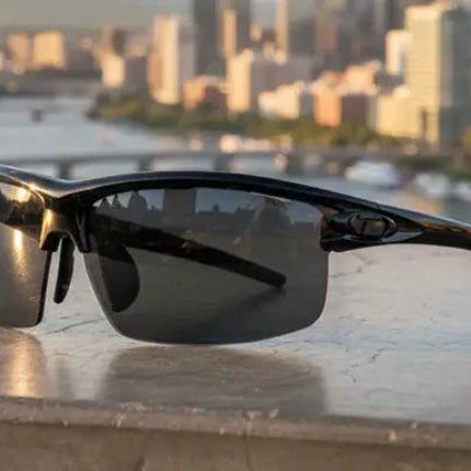 Black sunglasses on a ledge with a city skyline and river in the background