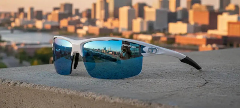 White sunglasses with blue mirrored lenses reflecting a city skyline