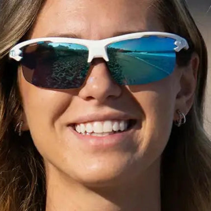 Woman smiling wearing white sunglasses with blue reflective lenses