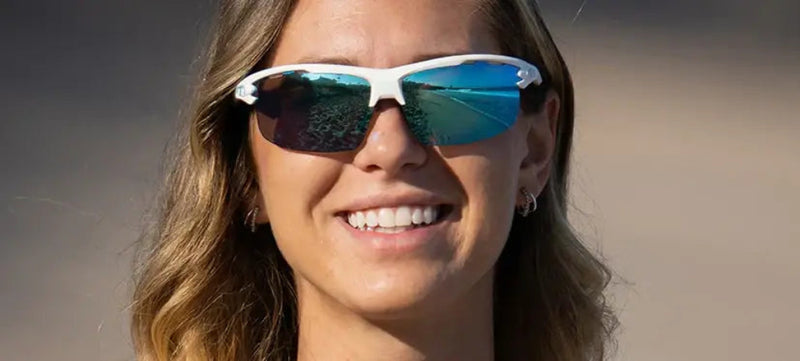 Woman smiling wearing white sunglasses with blue reflective lenses