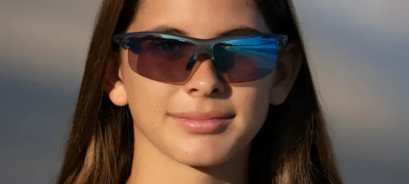 Young woman wearing dark sunglasses with blue reflective lenses