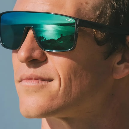 Man wearing sunglasses with a reflection of a lake and trees
