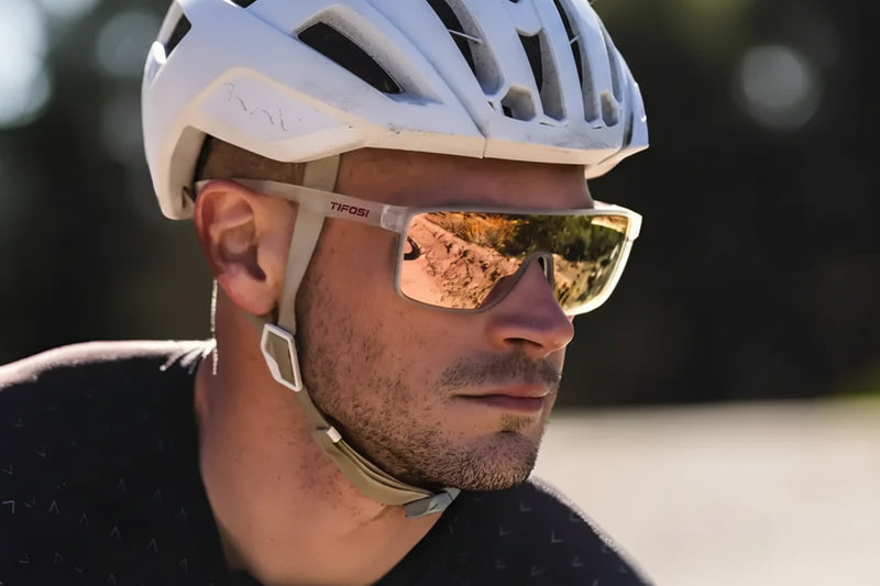 Man wearing a white cycling helmet and Tifosi sunglasses with reflective lenses