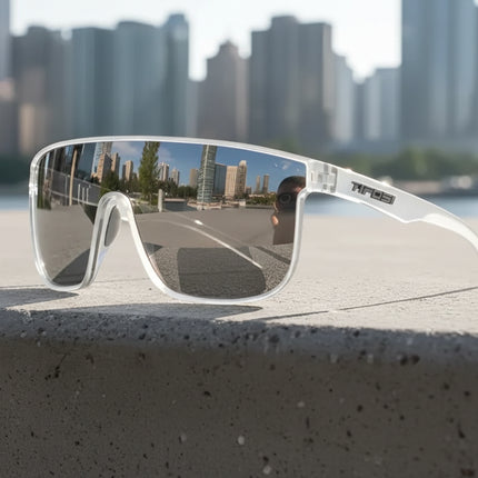 White sunglasses with reflective lenses on a concrete ledge, city skyline reflected in lenses