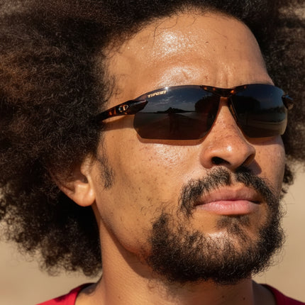 Man with dark curly hair and beard wearing sunglasses