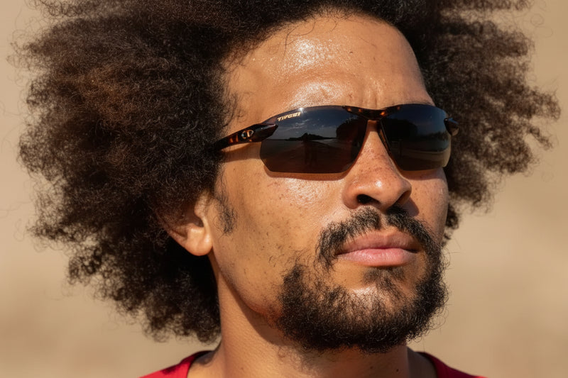 Man with dark curly hair and beard wearing sunglasses