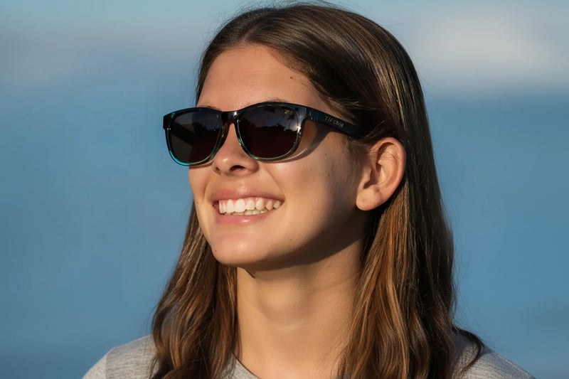 Woman wearing black and teal sunglasses with dark lenses