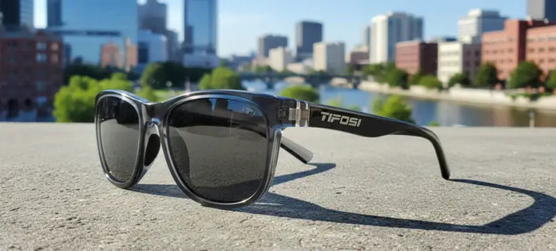 Tifosi sunglasses on a concrete surface with a city skyline and river in the background