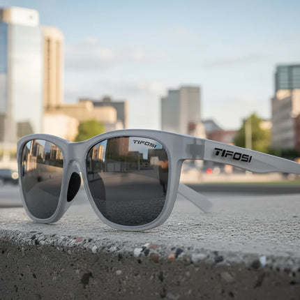 Tifosi sunglasses on a concrete ledge with a city skyline in the background