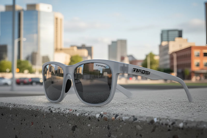 Tifosi sunglasses on a concrete ledge with a city skyline in the background
