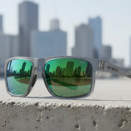 Grey sunglasses with green mirrored lenses reflecting a city skyline
