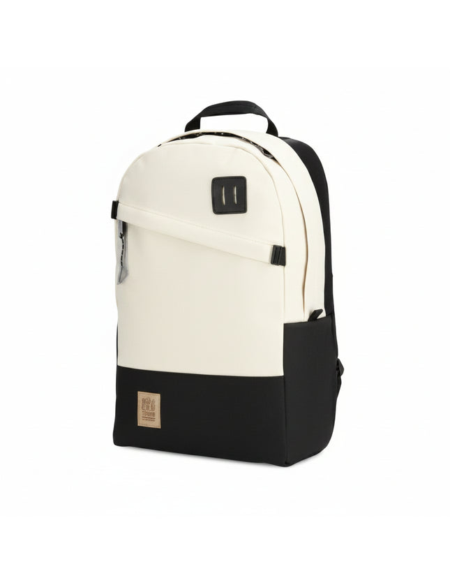 Two-tone backpack in cream and black with a front zipper pocket and a small brand patch