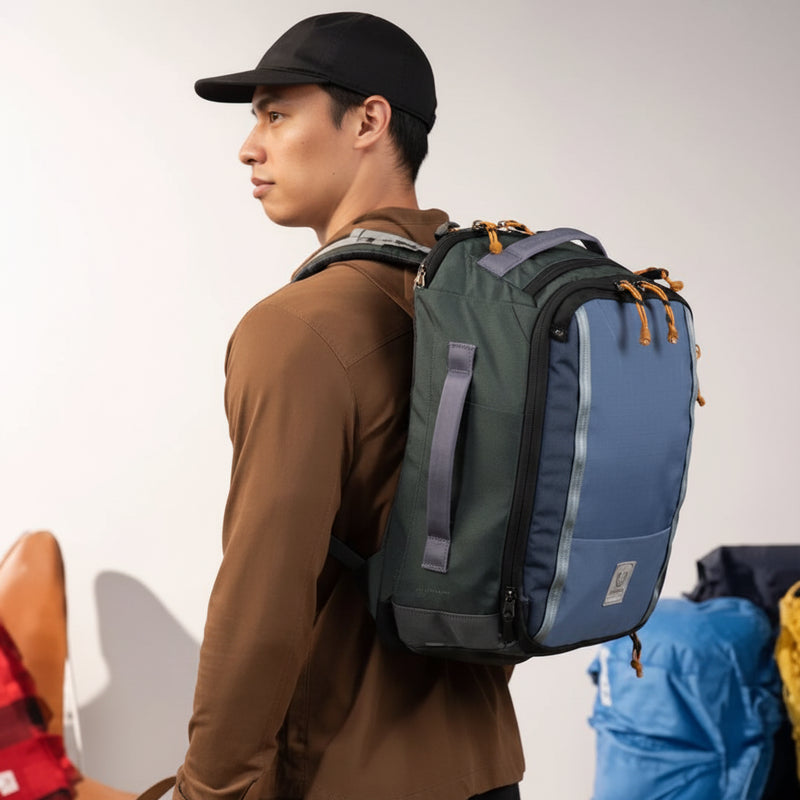 Man in a brown shirt and black cap wearing a blue and green backpack