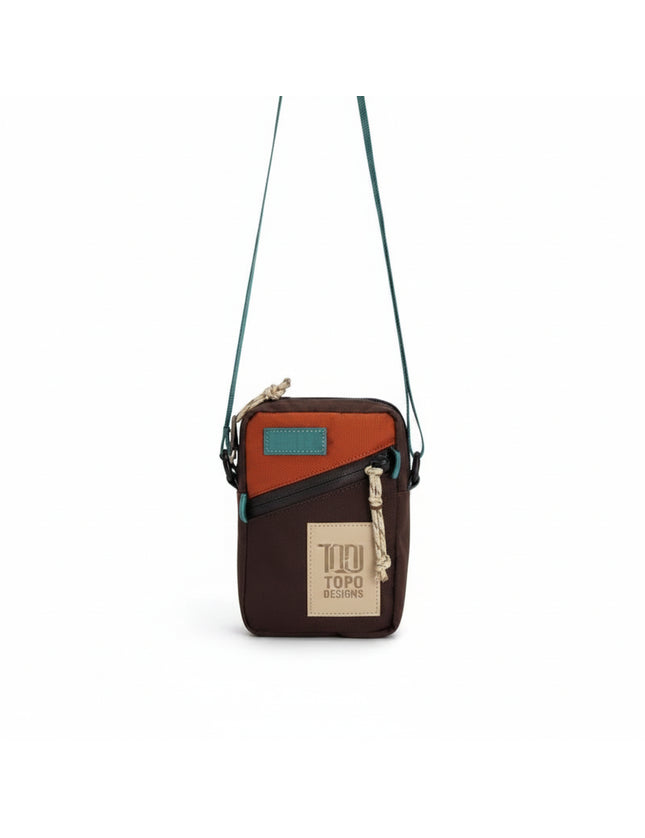 Brown and orange crossbody bag with a teal strap and a beige logo patch