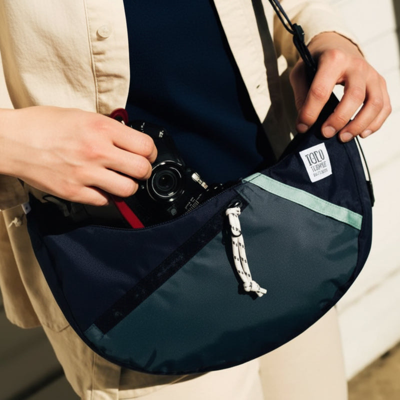 Person opening a dark blue and green fanny pack