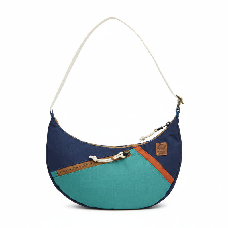 Blue and green crescent shaped shoulder bag with a white strap