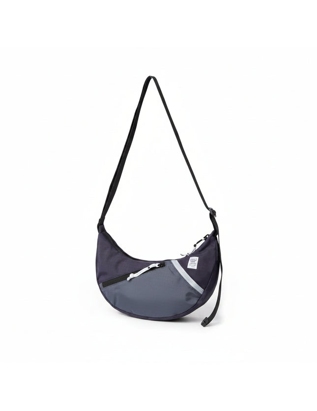 Dark blue and grey crescent-shaped shoulder bag with a black strap and white zipper details