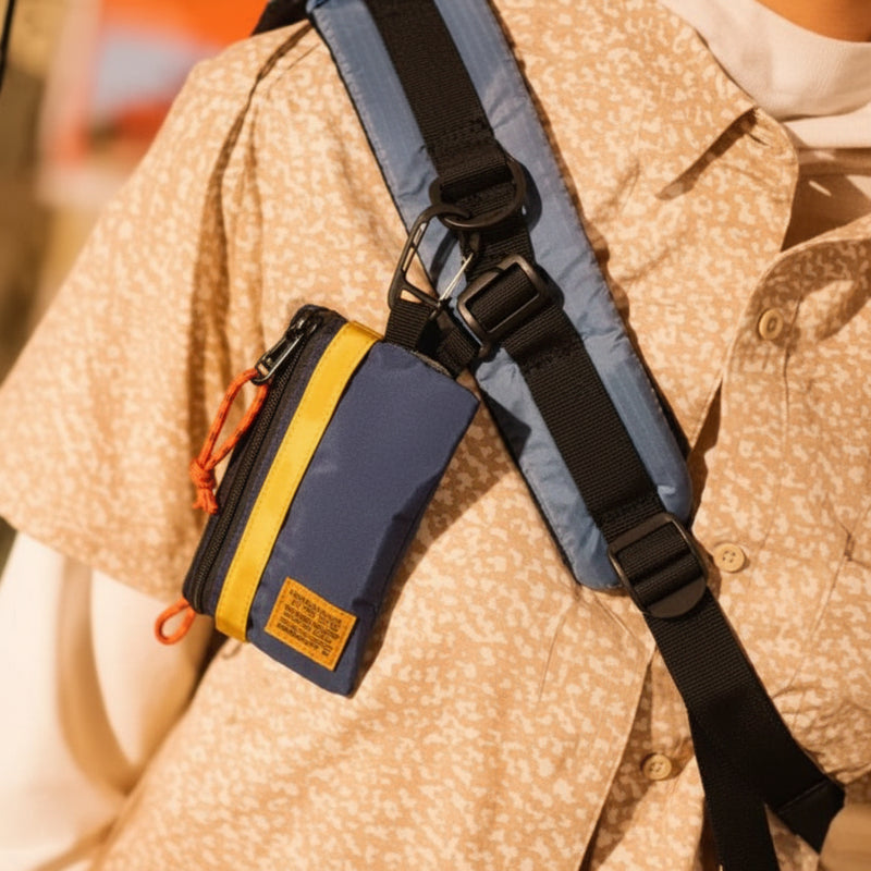 Person wearing a light brown patterned shirt with a blue and black strap across their shoulder