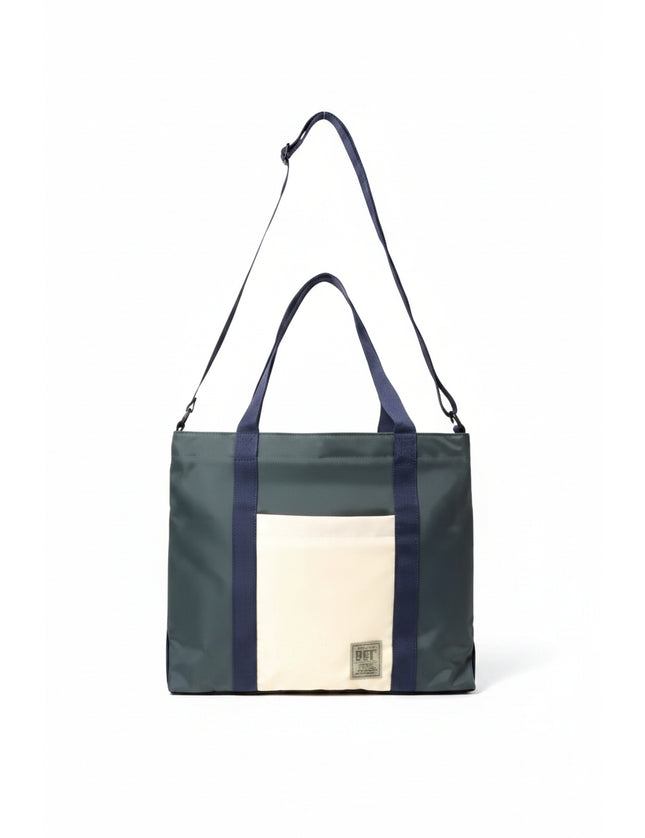 Dark green tote bag with navy blue straps and a cream front pocket