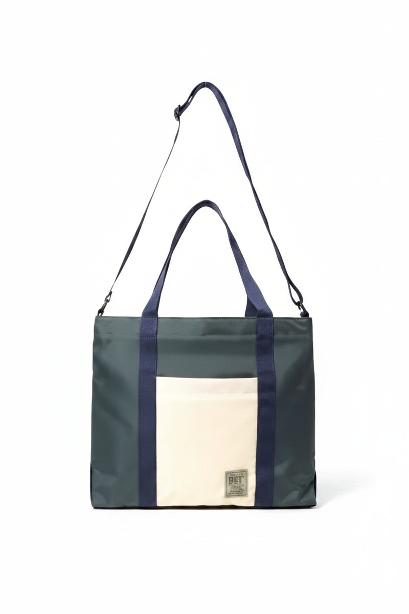 Dark green tote bag with navy blue straps and a cream front pocket