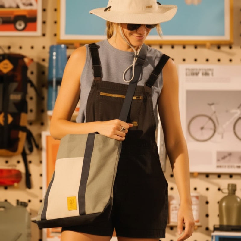 Woman wearing a sun hat and overalls, carrying a two-tone tote bag