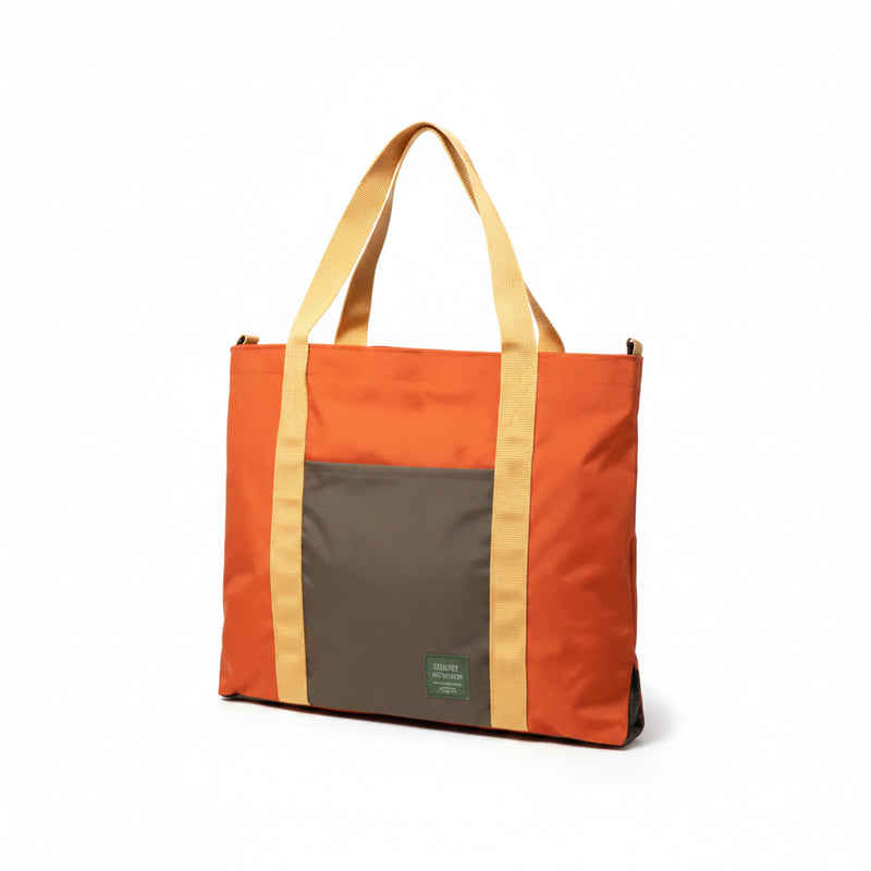 Orange tote bag with a dark grey front pocket and tan straps