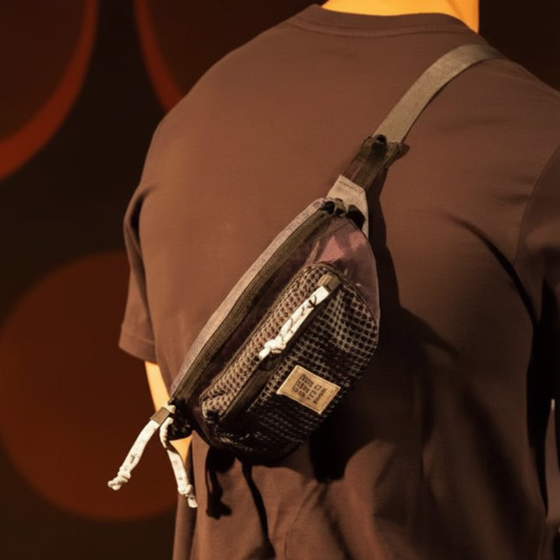 Man wearing a dark brown t-shirt with a black and grey fanny pack across his back
