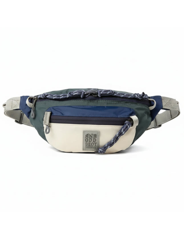 Green, navy, and cream fanny pack with a gray adjustable strap and a gray logo patch