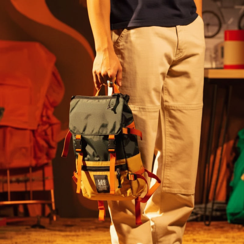 Person in tan pants holding a small green and yellow backpack