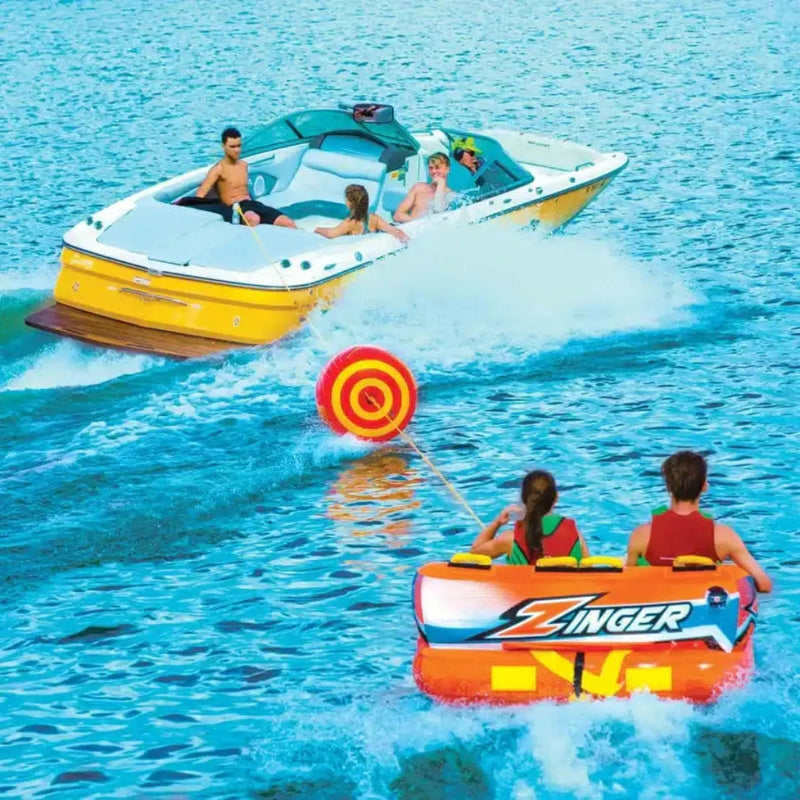 People on a boat and two people on an inflatable Zinger tube being pulled by the boat