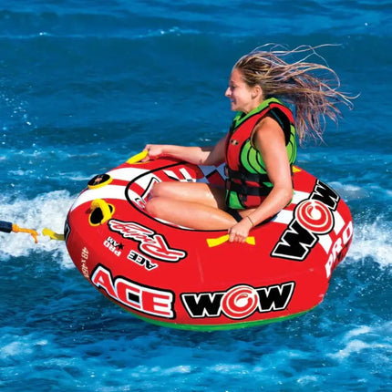 Woman in a red and green life vest riding a red and white inflatable tube on blue water